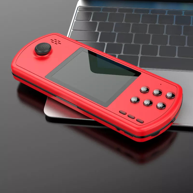 Red handheld retro gaming console with joystick and buttons resting on a laptop keyboard