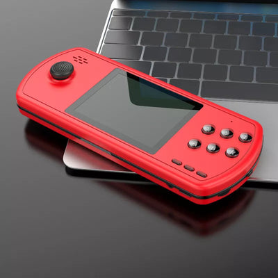 Red handheld retro gaming console with joystick and buttons resting on a laptop keyboard